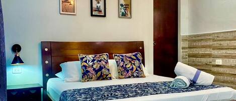 Un dormitorio con una cama de madera, una mesita de noche, una lámpara de pared y tres cuadros enmarcados.