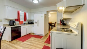 A compact kitchen with white cabinets, a dishwasher, a refrigerator, a microwave, a stove, and a dining area with a table and chairs. - 3 Mi to Stone Mountain Park: Quiet Family Getaway (Stone Mountain)