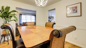 A dining area with a wooden table, woven chairs, a potted plant, and a modern chandelier. - 3 Mi to Stone Mountain Park: Quiet Family Getaway (Stone Mountain)