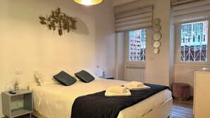 A bedroom with a bed, bedside table, lamp, wall art, window, and radiator. - Casa Cacio & Pepe 10 Min from Vatican Museums 5 Min from metro Cipro and Ottaviano (Roma)