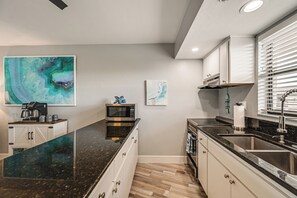 A modern kitchen with a granite countertop, stainless steel appliances, and artwork on the walls. - 2 Mi to Beach! Unit w/ Pool Access on Marco Island (Marco Island)