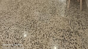Un comedor amplio con piso de terrazo, mobiliario blanco y una escalera que sube a otro nivel.