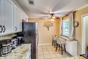 A kitchen with white cabinets, a black refrigerator, a coffee maker, and a wall clock. - 2 Mi to Downtown Savannah: Historic Home! (Savannah)