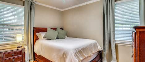 Un dormitorio con cama de madera, una mesita de noche, una lámpara y un ventilador de techo.