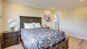 A bedroom with a large bed, a nightstand, a dresser, and a painting on the wall. - Easy SF Access! Spacious Family Home w/ Yard (Daly City)