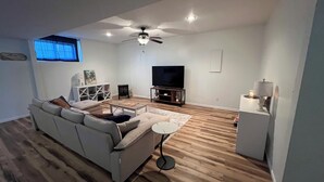 A modern living room with a sofa, a coffee table, a TV, and a ceiling fan. - Big Home right off I44 near Fort Leonard Wood (Saint Robert)