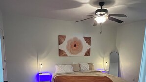 A bedroom with a bed, a ceiling fan, a nightstand, a lamp, and a chair. - Big Home right off I44 near Fort Leonard Wood (Saint Robert)