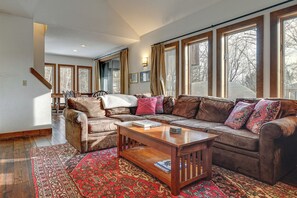 A spacious living room with a large sectional sofa, a wooden coffee table, and a red patterned rug.