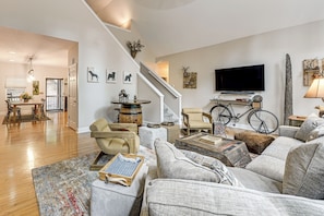 A living room with a sofa, coffee table, and a television. There is a staircase leading to another room.