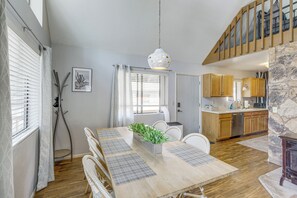 A dining area with a wooden table, white chairs, and a hanging light fixture. - Forest-Front Munds Park Cabin w/ ATV Access (Munds Park)