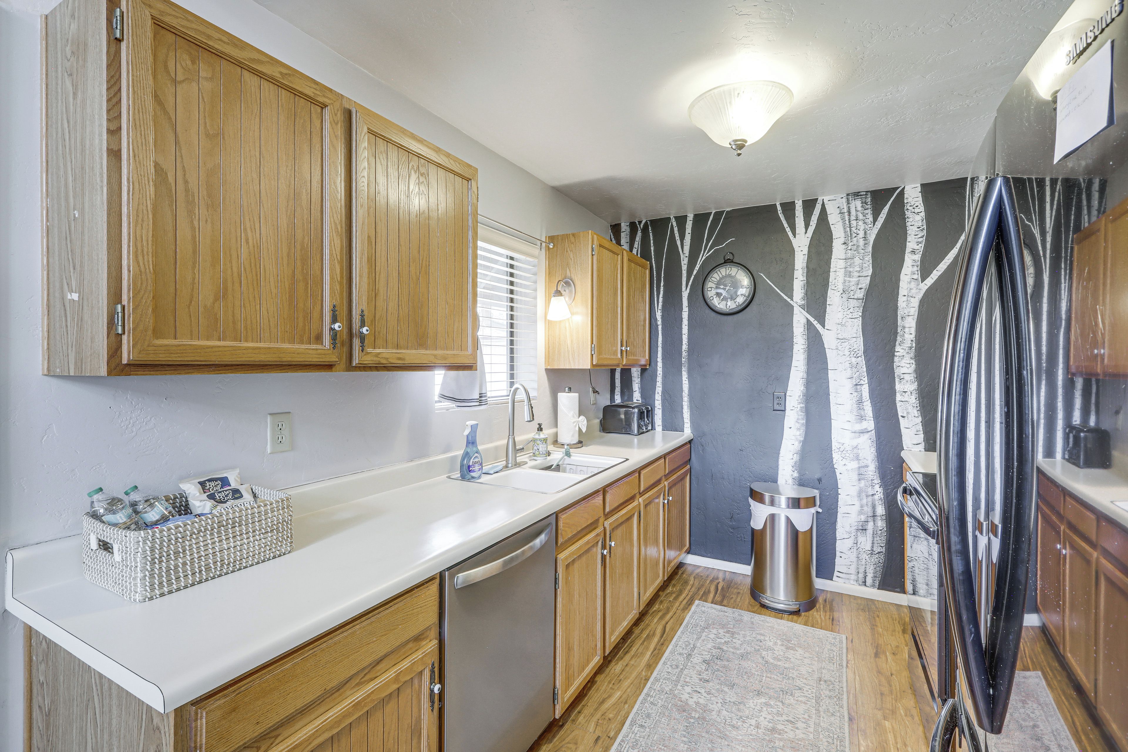 Una cocina con armarios de madera, un lavamanos de acero inoxidable y una pared con un mural de un árbol.