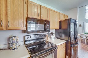 A kitchen with wooden cabinets, stainless steel appliances, and a countertop with kitchen utensils. - Forest-Front Munds Park Cabin w/ ATV Access (Munds Park)