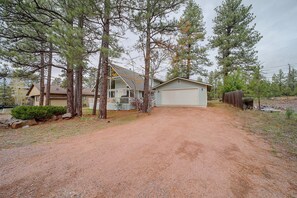 A two-story house with a garage, surrounded by tall pine trees. - Forest-Front Munds Park Cabin w/ ATV Access (Munds Park)