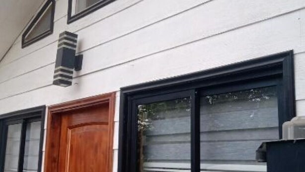 Ein Gebäude mit weißer Fassade, schwarzen Fensterrahmen und einer Holztür.