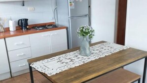 Eine Küche mit weißen Schränken, einer Holzauskładung, einem Herd und einem Tisch mit Blumen in einer Vase.