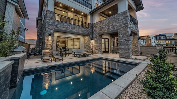 A two-story house with a swimming pool, stone exterior, and a balcony. - Modern Desert Color retreat designed for elevated group stays (St. George)