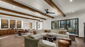 A spacious living area with a large sectional sofa, round ottomans, and a dining area with wooden tables and chairs. - Modern Desert Color retreat designed for elevated group stays (St. George)