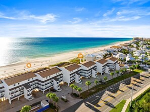 Un hôtel situé sur la côte, composé de plusieurs bâtiments à étages, avec un accès direct à la plage et un espace de stationnement.