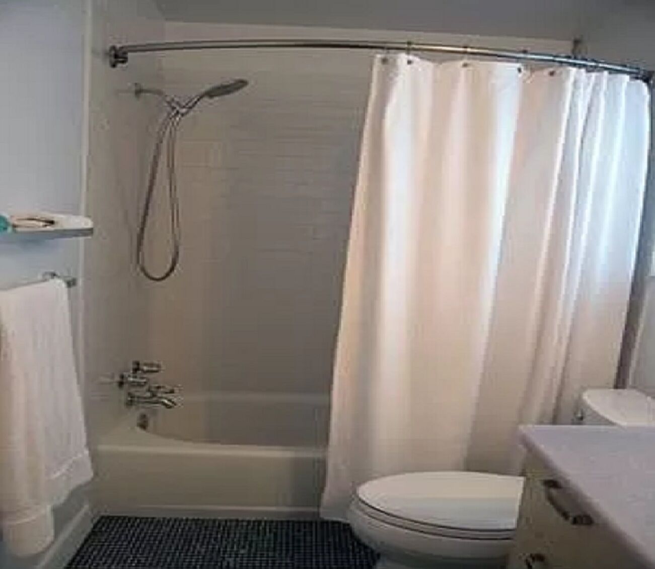 Un baño con ducha, inodoro y toallero.