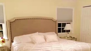 Ein Bett mit Holzrahmen und weißer Bettwäsche in einem Zimmer mit Fenster und Nachttisch.