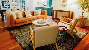 Ein Wohnzimmer mit einer Couch, Sesseln, einem Couchtisch und einem Teppich.