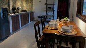 Uma cozinha moderna com uma ilha central, uma mesa de jantar posta com pratos brancos e uma cadeira de madeira.