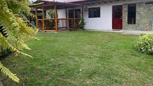 A house with a red door, a stone wall, and a fenced porch. - El Rosal Cabin (Filandia)