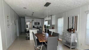 A modern kitchen with a central island, stainless steel appliances, and a dining area with a wooden table and grey chairs. - Welcome Beautiful and Relax residence in Key Largo with new Canal (Key Largo)