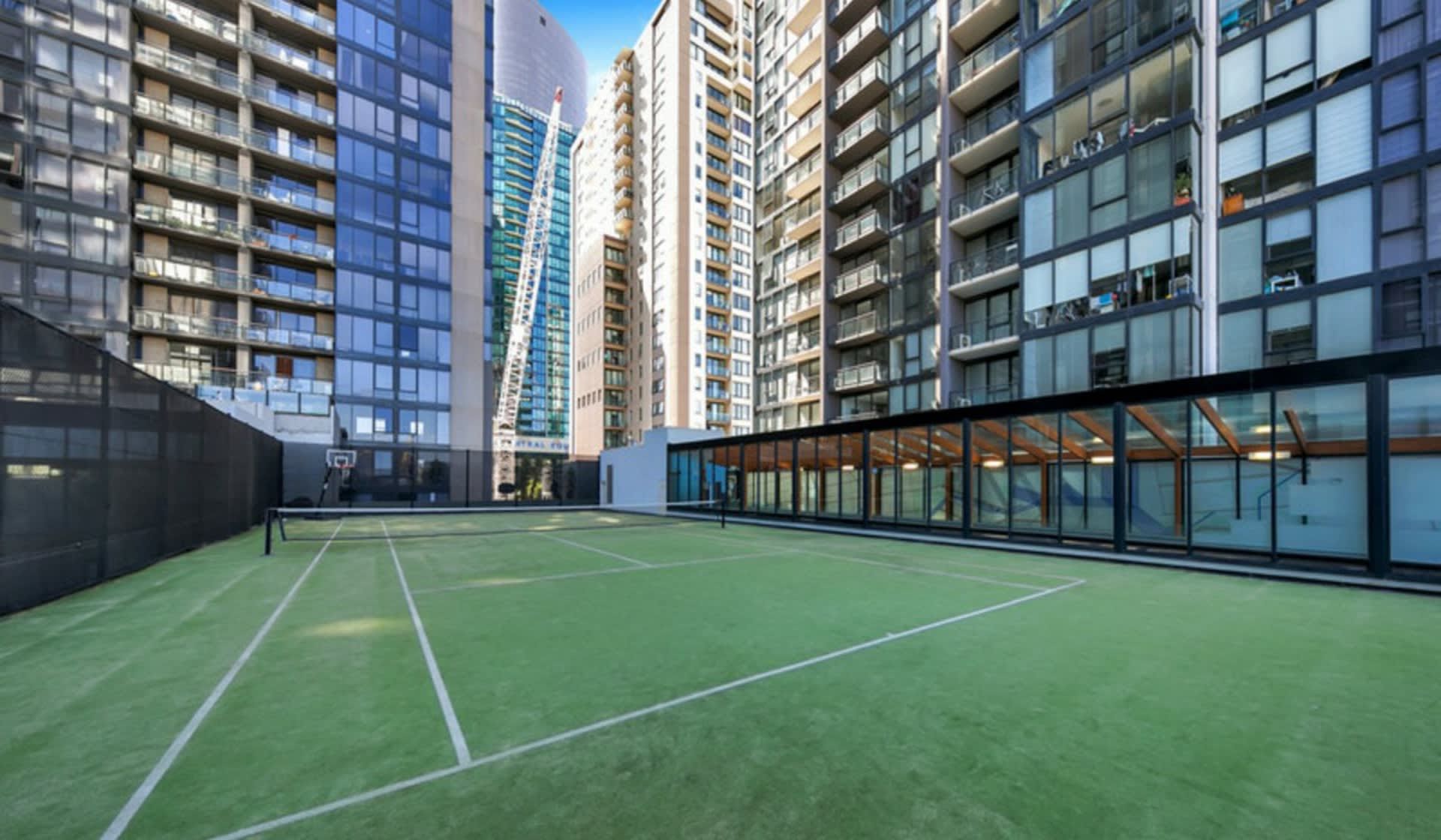 A tennis court surrounded by high-rise residential buildings.