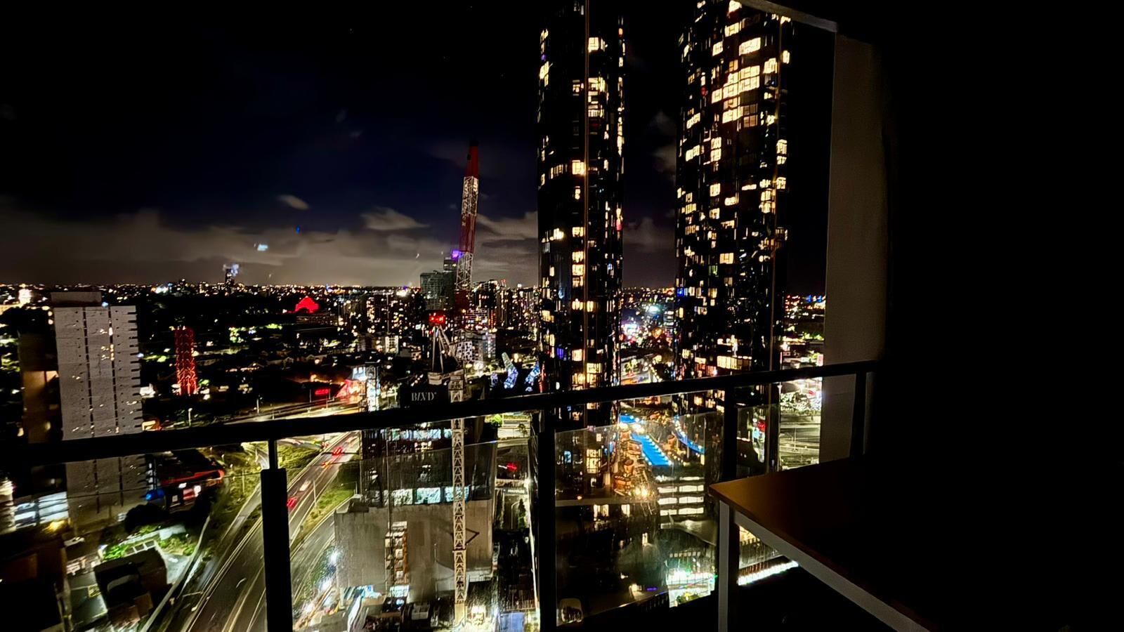 A nighttime cityscape with illuminated buildings and a view of a bridge.