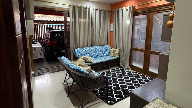 Una sala de estar con sofá, mesa de centro, ventilador de techo y alfombra estampada.