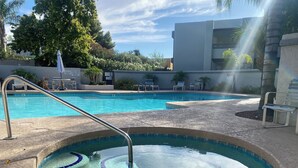 A swimming pool with a small hot tub, surrounded by lounge chairs and a palm tree. - Bright spacious 2-bedrm 2-bath, upstairs condo, Guard-gated in the Biltmore area (Phoenix)