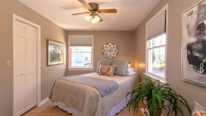 A bedroom with a bed, a ceiling fan, a window, and a plant. - The Mountain View Cottage at Blue Ridge Hideaways (Weaverville)