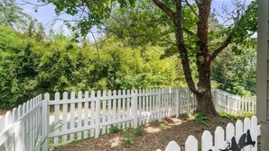 A white picket fence surrounding a tree-lined area with mulch and a bird silhouette decoration. - The Mountain View Cottage at Blue Ridge Hideaways (Weaverville)