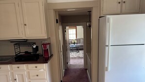 A kitchen with wooden flooring, white cabinets, a refrigerator, and a coffee maker. - Experience comfort in our Danvers, MA 3-bedroom  (Danvers)