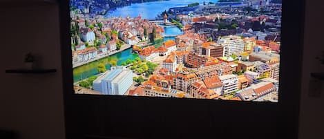 A television displaying a cityscape with a river and mountains.