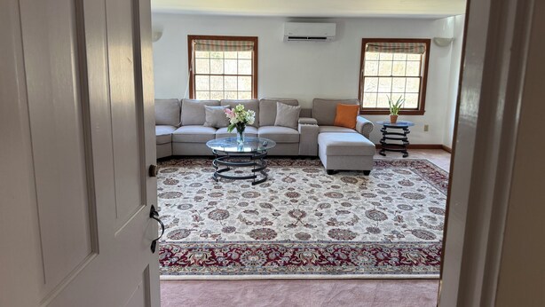 A living room with a sofa, ottoman, coffee table, and a patterned rug. - Experience comfort in our Danvers, MA 3-bedroom  (Danvers)