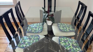 A dining table with a glass top, surrounded by chairs with floral cushions, and a potted plant on the table. - Experience comfort in our Danvers, MA 3-bedroom  (Danvers)