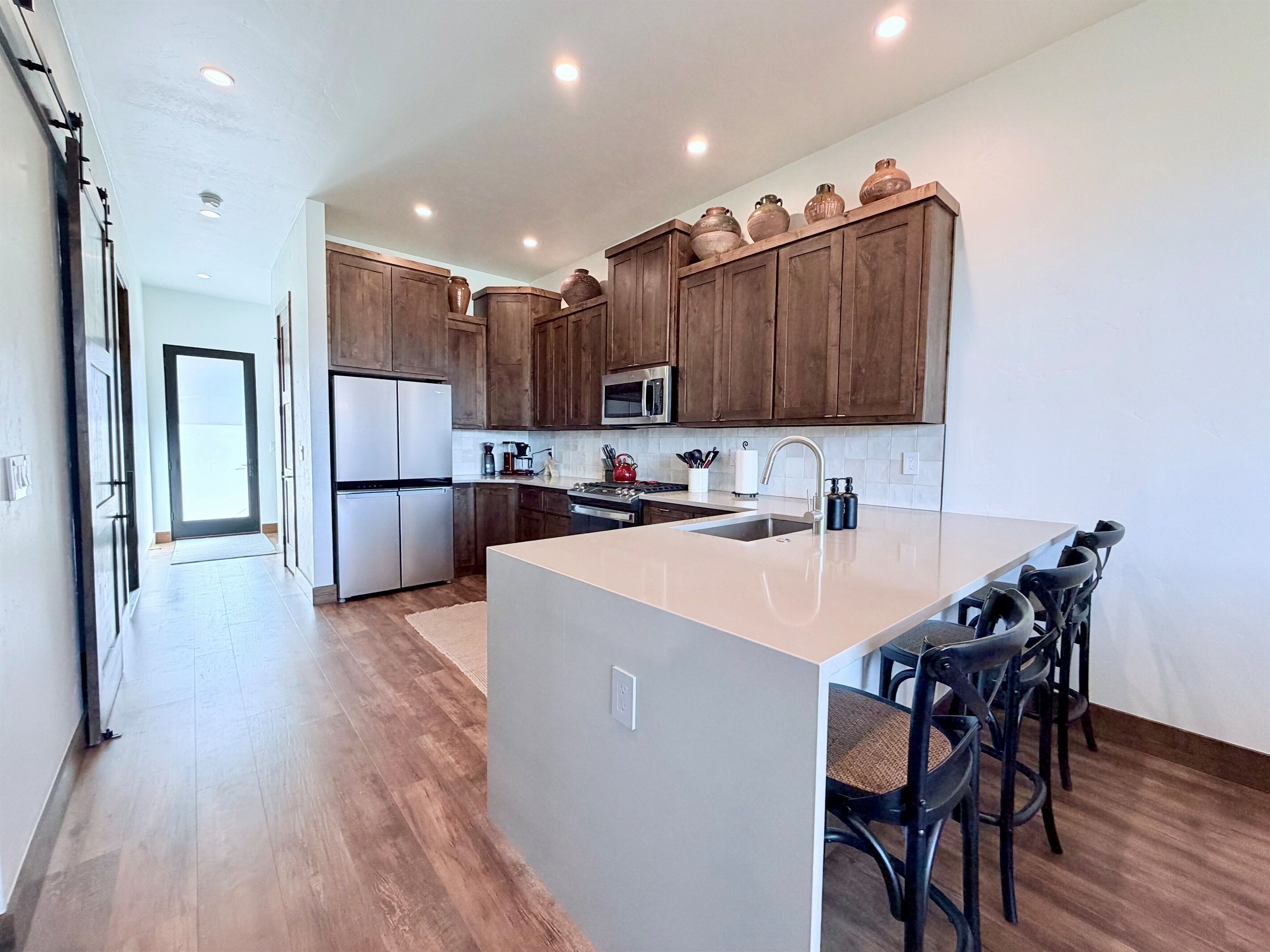 A modern kitchen with wooden cabinets, stainless steel appliances, and a central island with bar stools.