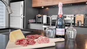 Eine Küchenarbeitsplatte mit einer Flasche Moët & Chandon Champagner, einem Glas, einem Schneidebrett mit Käse und Salami sowie einem Messer.