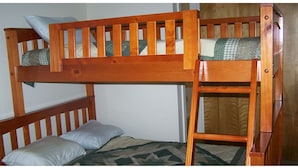 Een stapelbed met een ladder, twee kussens en een bedovertrek met een patroon.