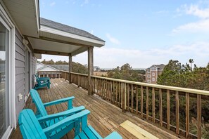 A wooden deck with blue Adirondack chairs, a covered area, and a view of buildings and trees. - Luxury Retreat w/SOUND VIEWS! Private Pool & Arcade (Salvo)