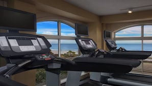 Ein Fitnessraum mit zwei Laufbändern, großen Fenstern und Meerblick.