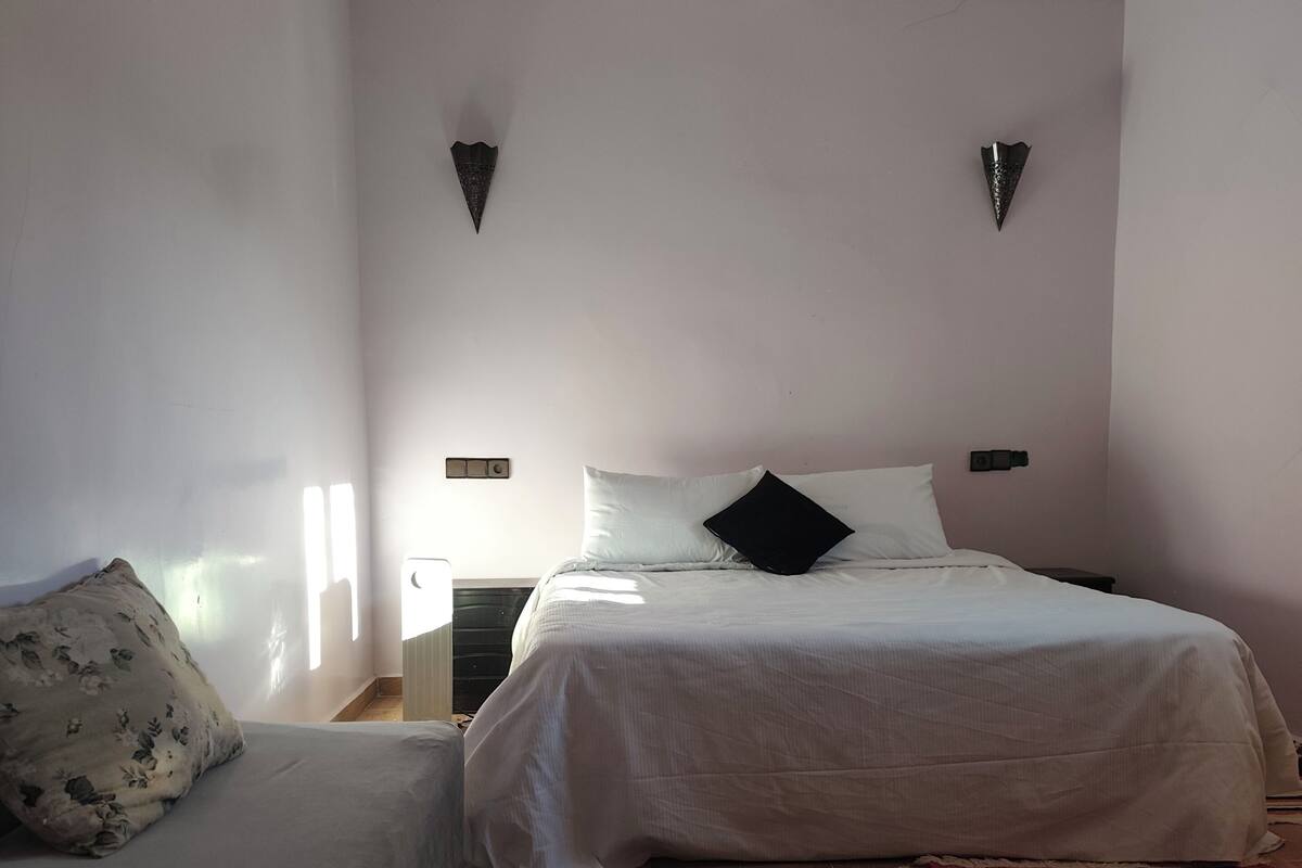 Ein Schlafzimmer mit einem Bett, einem Schlafsofa, einem Teppich und einem Nachttisch.