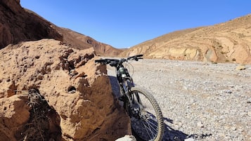 Een mountainbike geparkeerd tegen een rotsformatie in een woestijnlandschap.