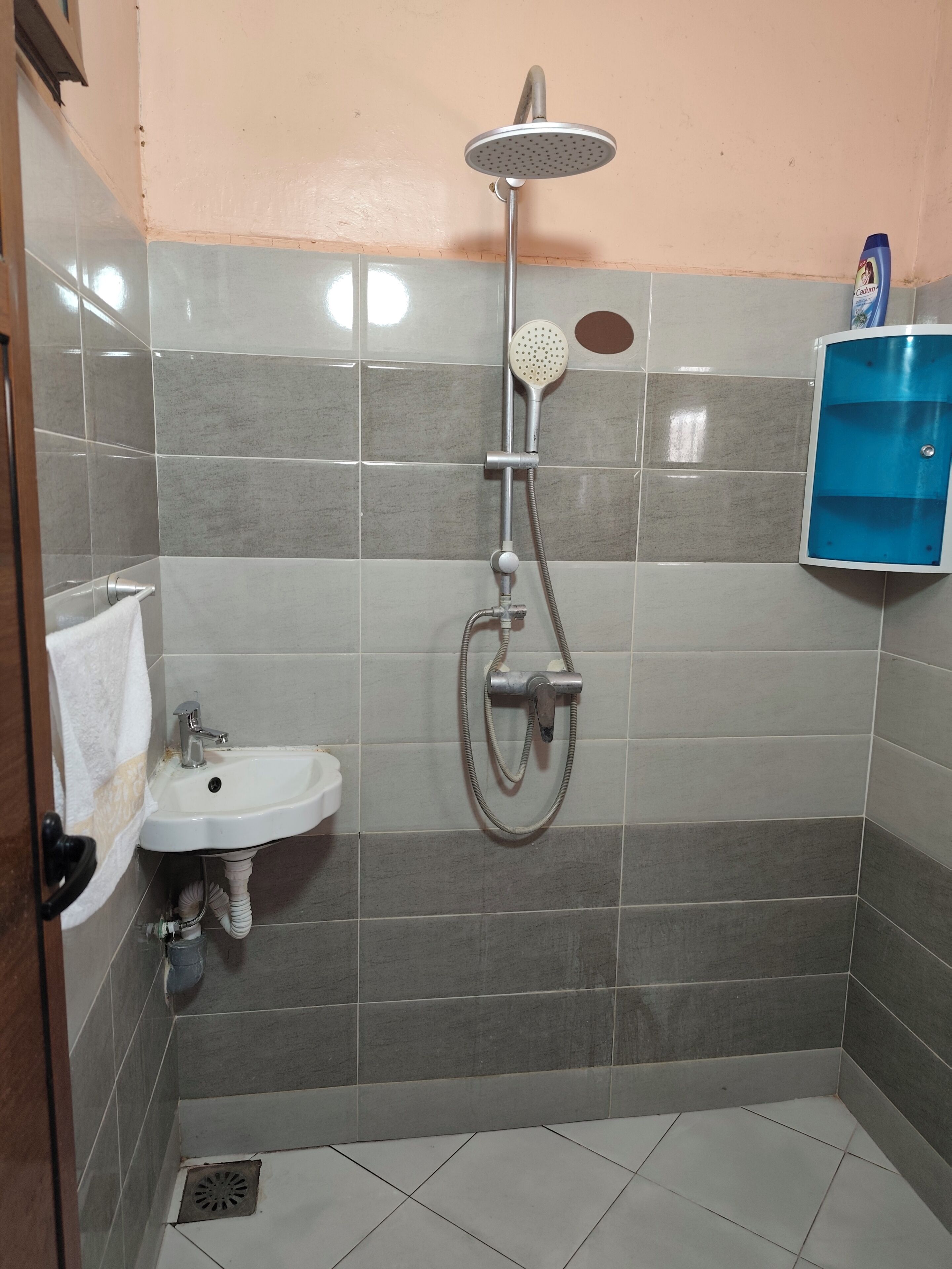 A bathroom with a shower, sink, and blue cabinet.