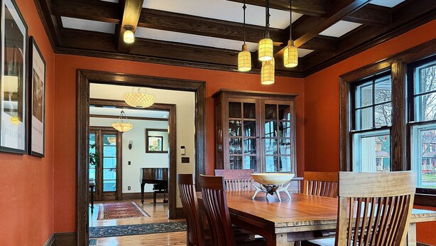 A dining area with a wooden table and chairs, a patterned rug, and a chandelier. - Elegant Historic Home near University of Rochester (Rochester)