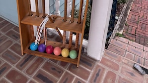 A wooden rack with colorful balls and wooden mallets on a porch.