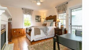A bedroom with a bed, bedside table, lamp, and a view of the outdoors.