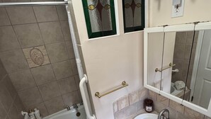 A bathroom with a bathtub, sink, vanity, and a mirror.